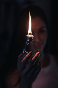 A glowing flame inside a light bulb held by a woman, creating a warm and mysterious ambiance.