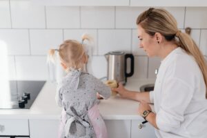 A mother helps her young daughter bake on a kitchen counter, creating a precious bonding moment.